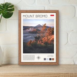 Könnte beinhalten: Ein gerahmter Druck des Mount Bromo in Indonesien. Das Bild zeigt eine vulkanische Landschaft mit einem Berg im Hintergrund und einem nebligen Vordergrund. Der Druck enthält den Namen "Mount Bromo" in fetter Schrift, den Ort "Java, Indonesien" und die Koordinaten "7° 54' 39.9028" S, 112° 57' 3.7908" E".