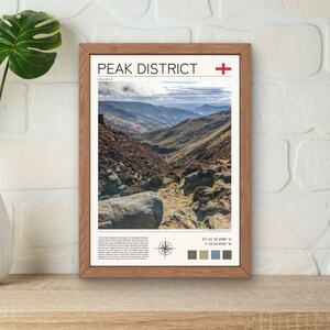 May include: A framed print featuring a photograph of a mountainous landscape in the Peak District, England. The print includes the name "Peak District" in bold font, the coordinates 53.22° 50.3988' N 1.52° 34.4928' W, and a compass rose.