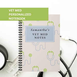 Può includere: Un quaderno a spirale con una copertina beige chiaro con un motivo ripetitivo di simboli medici verdi e blu. La copertina ha un rettangolo blu chiaro con il testo "Samantha's Vet Med Notes".