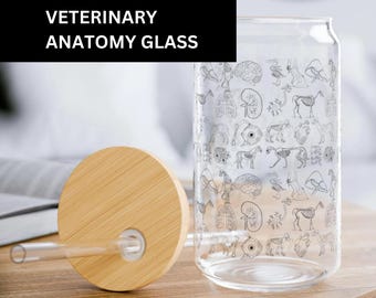 Pode incluir: Um copo de vidro transparente com tampa de bambu e um canudo. O copo tem uma impressão em preto e branco de várias ilustrações de anatomia animal. O texto "VETERINARY ANATOMY GLASS" está impresso em um fundo preto.