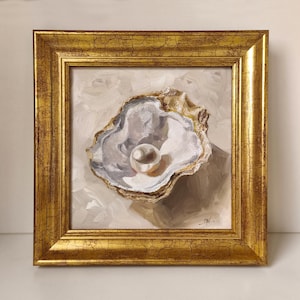 Könnte beinhalten: Ein Ölgemälde einer geöffneten Austernschale mit einer einzelnen weißen Perle in Creme-, Grau- und Weißtönen. Das Kunstwerk befindet sich in einem quadratischen, verzierten, goldfarbenen Rahmen mit einer deutlich sichtbaren Rissstruktur.