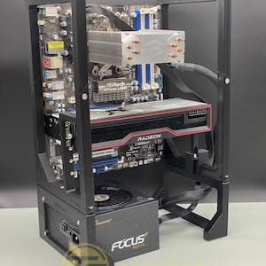 Op de afbeelding: Een zwarte computerbehuizing met een transparant zijpaneel, waar een moederbord, een grafische kaart, een CPU-koeler en een voeding zichtbaar zijn. De voeding is een Seasonic Focus Gold.