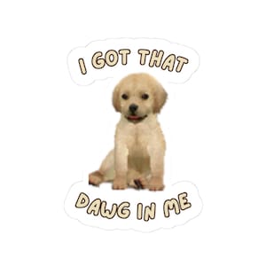 May include: A sticker featuring a light tan puppy with a pink tongue, sitting and looking forward. The text "I GOT THAT" is above the puppy, and "DAWG IN ME" is below, all in a brown, outlined font. The sticker has a white background.