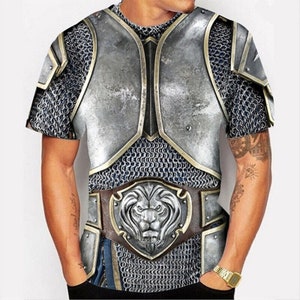 May include: A short-sleeved t-shirt featuring a graphic print of silver armour and a lion's head. The armour has a chainmail design and a gold belt with a lion's head buckle.