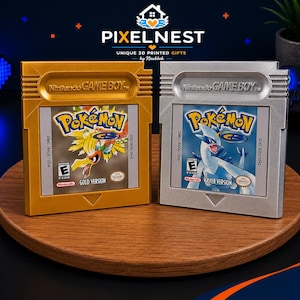 Könnte beinhalten: Zwei Nintendo Game Boy Videospielkassetten, eine goldene und eine silberne, mit Etiketten für Pokémon Gold Version und Pokémon Silver Version. Jede Kassette zeigt das Nintendo Game Boy Logo, das E-Bewertungssymbol und die jeweiligen Spieletitel.