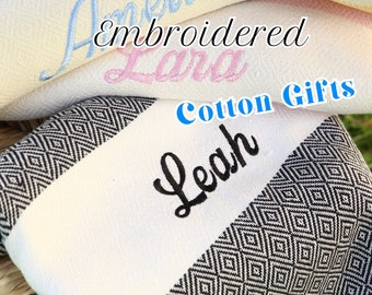 Può includere: Asciugamani in cotone bianco con motivi a rombi neri e nomi ricamati, "Leah", "Lara" e "Amelia". Gli asciugamani sono impilati e l'asciugamano superiore ha il testo "Embroidered Cotton Gifts".