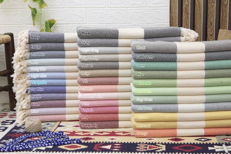 Pu&ograve; includere: Una pila di asciugamani turchi in vari colori, tra cui blu navy, indaco, blu turchese, menta, blu bambino, blu chiaro, turchese, verde acqua, salmone, rosa cipria, rosa, fucsia, rosso, bordeaux, giallo, senape e arancio.