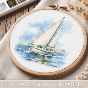 May include: A watercolor painting of a sailboat on the water with a blue sky and white clouds in the background. The sailboat is white with a brown deck and a brown mast. The water is blue and green. The painting is in a wooden embroidery hoop.
