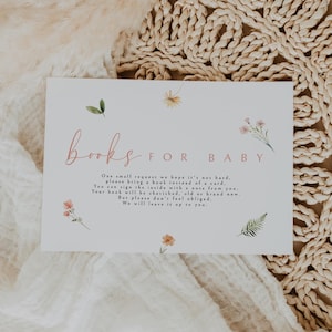 Puede incluir: Una tarjeta blanca con ilustraciones florales rosas y verdes. El texto en la tarjeta dice "libros para bebé". La tarjeta solicita a los invitados que traigan un libro en lugar de una tarjeta para el bebé.