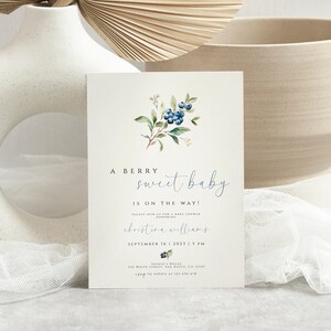 Może przedstawiać: Zaproszenie na baby shower z akwarelową ilustracją jag&oacute;d i zielonych liści. Tekst brzmi "A berry sweet baby is on the way!" z imieniem gospodarza, datą i godziną.