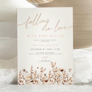 Peut inclure: Une invitation à une baby shower avec l'inscription "falling in love" en écriture élégante. L'invitation comprend les détails pour Baby Miller, Rachel Miller, ainsi que la date, l'heure et le lieu de l'événement. Des illustrations florales aux tons sourds ornent le bas.