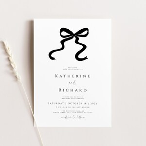 May include: A black and white wedding invitation with a black ribbon bow at the top. The text reads "Katherine and Richard, Saturday October 18, 2026, 5 o'clock in the afternoon, White Street Restaurant, reception to follow."
