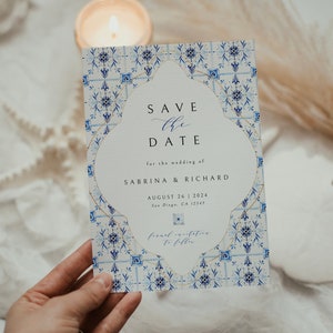Puede incluir: Una invitación de boda con un diseño de azulejos azules y blancos. El texto dice "Save the Date" para Sabrina & Richard, 26 de agosto de 2024, en San Diego, CA. La invitación tiene un borde decorativo.