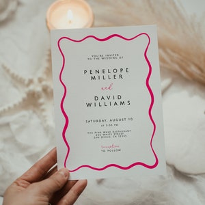May include: A white wedding invitation with pink wavy border. The invitation reads "You're invited to the wedding of Penelope Miller and David Williams. Saturday, August 10 at 5:00 PM. The Pink Wave Restaurant, 256 White Street, San Diego, CA 12345. Reception to follow."