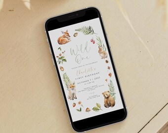 May include: A digital invitation for a first birthday party with a woodland theme. The invitation features a white background with illustrations of a deer, a rabbit, a fox, and a bear. The text on the invitation reads "Wild One" and "Charlotte's First Birthday".