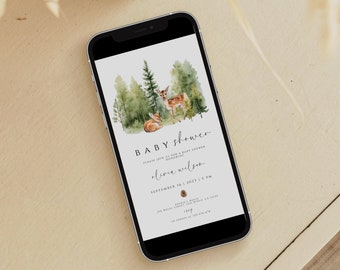 以下が含まれることがあります： スマートフォン画面に表示されたベビーシャワーの招待状。招待状には、2頭の鹿がいる森の風景の水彩画が描かれています。テキストには「ベビーシャワー」と「オリビア・ウィルソン」とイベントの日時が書かれています。