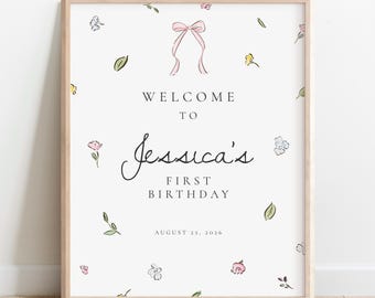 Puede incluir: Un letrero de bienvenida enmarcado para el primer cumpleaños de Jessica, con un marco de madera clara. El fondo blanco está adornado con delicadas ilustraciones florales y de hojas, y un lazo rosa. El texto dice "Bienvenida al Primer Cumpleaños de Jessica, 25 de agosto de 2026."