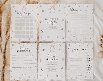 May include: A set of baby shower game cards with floral and bow illustrations. The cards include "Baby Bingo," "Diaper Raffle," "Who's That Baby," "Baby Predictions," "Late Night Diapers," and "Guess Who." A wooden rattle is also present.