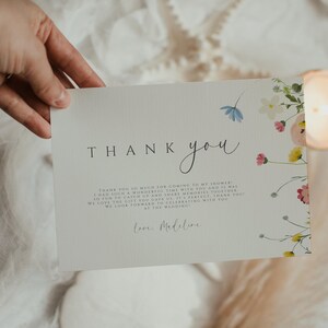 May include: A thank you card with a floral design and the text "THANK you" in a handwritten font. The card reads "Thank you so much for coming to my shower! I had such a wonderful time with you and it was so fun to catch up and share memories together. We love the gift you gave us. It's perfect. Thank you! We look forward to celebrating with you at the wedding. Love, Madeline."
