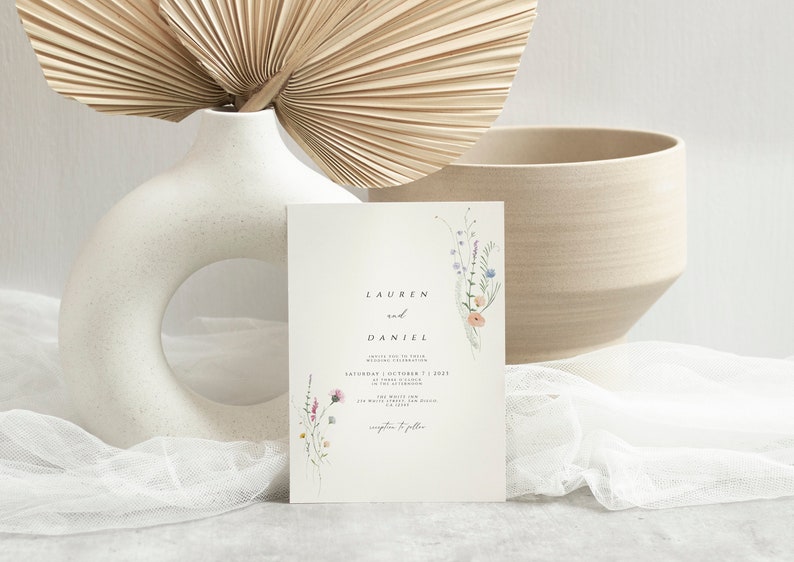 May include: A wedding invitation with a floral design featuring a bouquet of watercolor wildflowers in shades of pink, purple, and blue. The invitation reads "Lauren and Daniel" with the date and time of the wedding ceremony.