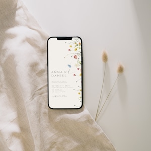 May include: A smartphone displaying a wedding invitation with a floral design. The invitation reads "Anna and Daniel" and includes the date "October 7, 2021".