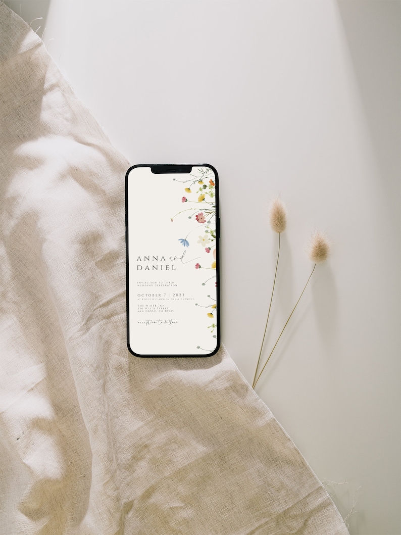 May include: A smartphone displaying a wedding invitation with a floral design. The invitation reads "Anna and Daniel" and includes the date "October 7, 2021".