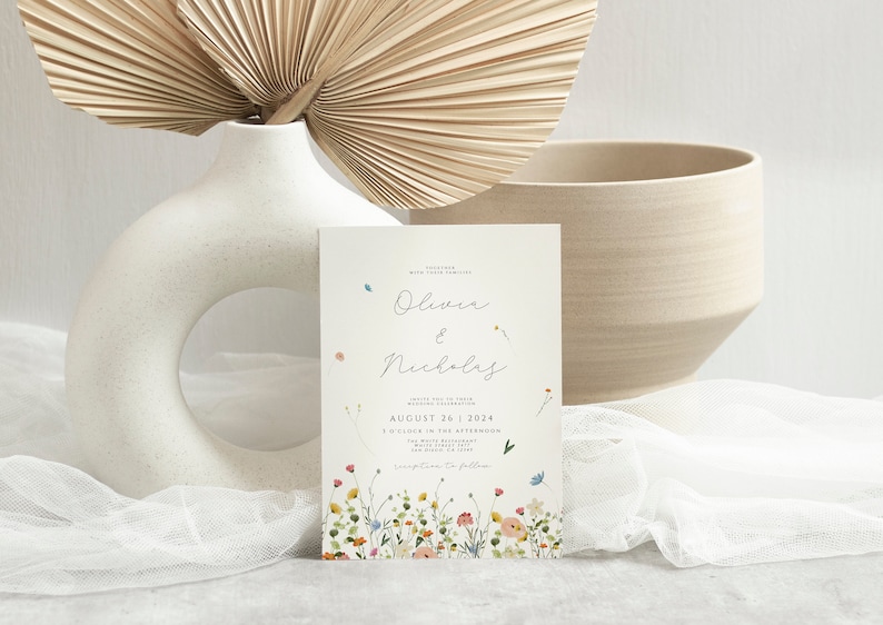 May include: A wedding invitation card with a white background and a floral border. The card features the names "Olivia & Nicholas" in cursive script and the date "August 26, 2024".