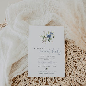 Może przedstawiać: Zaproszenie na baby shower z akwarelową ilustracją jag&oacute;d i zieleni. Zaproszenie zawiera napis "A Berry Sweet Baby Is On The Way!" oraz datę i godzinę baby shower, imię osoby, kt&oacute;rej dotyczy uroczystość, oraz miejsce.