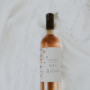 May include: A bottle of rose wine with a floral design label that says "Cheers to the future Mrs. Wilson".