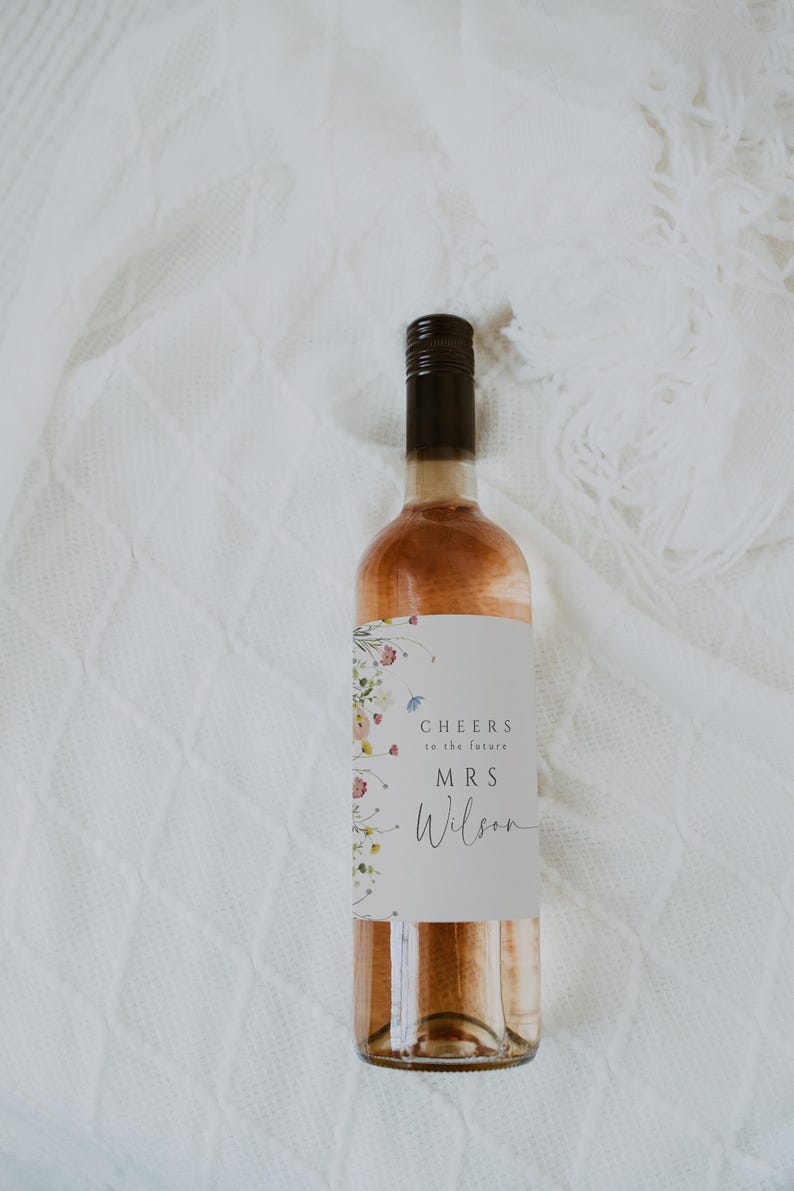 May include: A bottle of rose wine with a floral design label that says "Cheers to the future Mrs. Wilson".