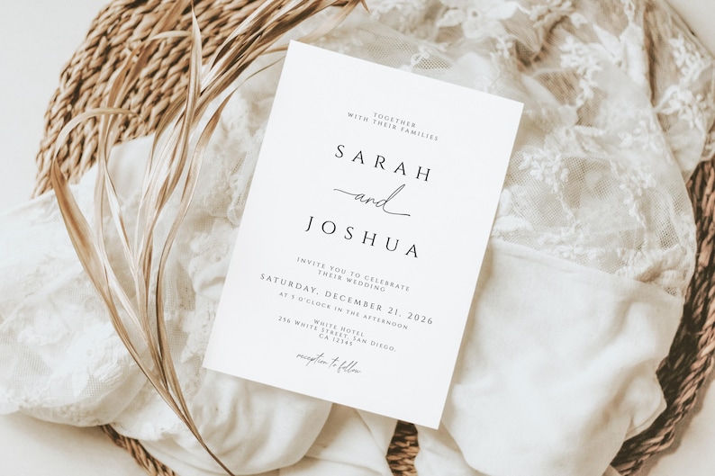 K&ouml;nnte beinhalten: Eine wei&szlig;e Hochzeitseinladung mit schwarzem Text, mit den Namen "Sarah und Joshua" in eleganter Schrift. Die Einladung enth&auml;lt Datum, Uhrzeit und Ort der Hochzeit. Die Einladung liegt auf einem wei&szlig;en Spitzentuch und einem geflochtenen Korb.