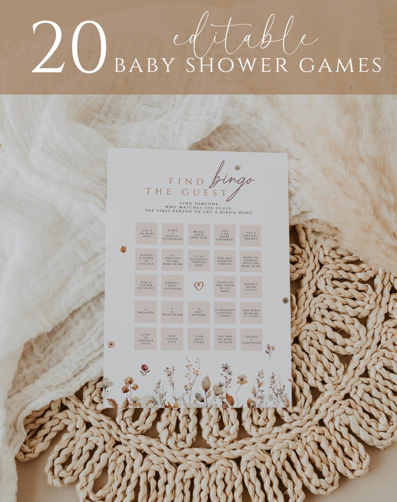 May include: A baby shower game card with the text "20 Editable Baby Shower Games" at the top. The card features a "Find the Guest Bingo" game with floral accents and a neutral color palette. The card is on a woven mat.