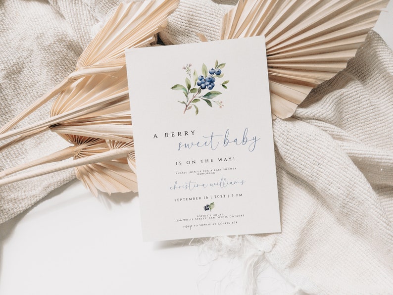 Może przedstawiać: Białe zaproszenie na baby shower z akwarelową ilustracją jag&oacute;d i zielonych liści. Tekst brzmi "A berry sweet baby is on the way!" i zawiera imię "christine williams" oraz datę "September 16, 2023, 3 PM".