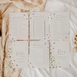 May include: Five printable baby shower game cards with floral designs. The games include "Would She Rather", "Honey Do List", "What's in Your Phone", "Over or Under", and "Ring Hunt".