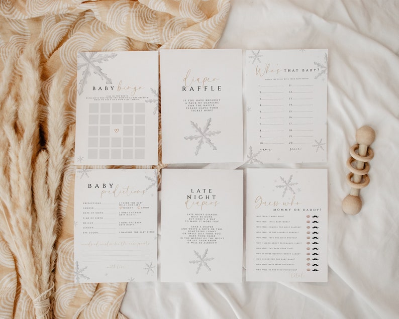 Pode incluir: Um conjunto de cart&otilde;es de jogo de ch&aacute; de beb&ecirc; imprim&iacute;veis com um tema de inverno. Os cart&otilde;es apresentam flocos de neve e o texto "Baby Bingo", "Rifa de fraldas", "Quem &eacute; esse beb&ecirc;?", "Previs&otilde;es de beb&ecirc;", "Fraldas noturnas" e "Adivinhe quem &eacute; a mam&atilde;e ou o papai?"