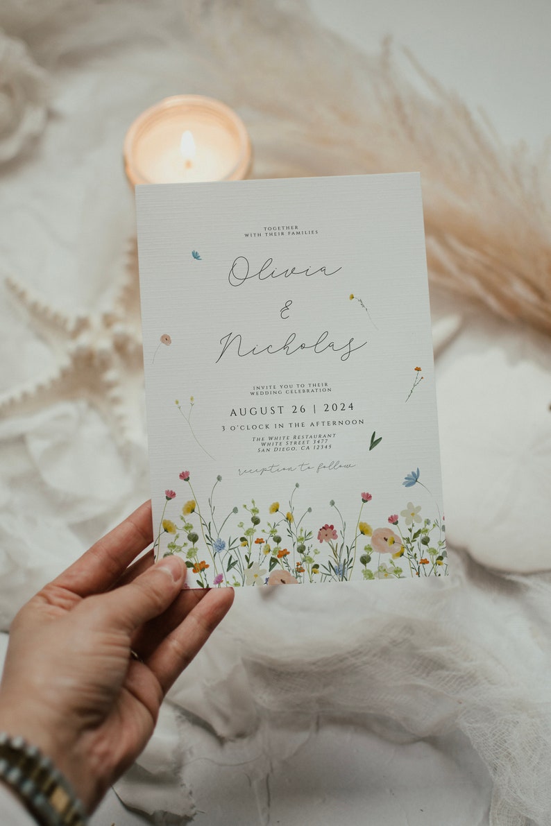May include: A wedding invitation featuring a floral design. The invitation is for Olivia and Nicholas and is set for 26 August 2024 at 3 o'clock in the afternoon at The White Restaurant in San Diego, CA 12345. The invitation states "reception to follow".