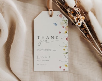 May include: A white tag with the words "THANK YOU" in black and script font. The tag is decorated with a floral design in pink, yellow, and blue. The tag also includes the text "FOR SHOWERING OUR BABY WITH LOVE" and "Lauren's BABY SHOWER 06.10.2026".