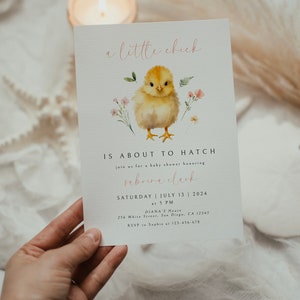 May include: A baby shower invitation with a watercolor illustration of a yellow chick with pink flowers. The text reads "a little chick is about to hatch" and includes the name "Sabrina Clark", the date "Saturday, July 13, 2024", the time "at 5 PM", the location "Diana's House, 256 White Street, San Diego, CA 12345", and the RSVP information "RSVP to Sophie at 123-456-678".