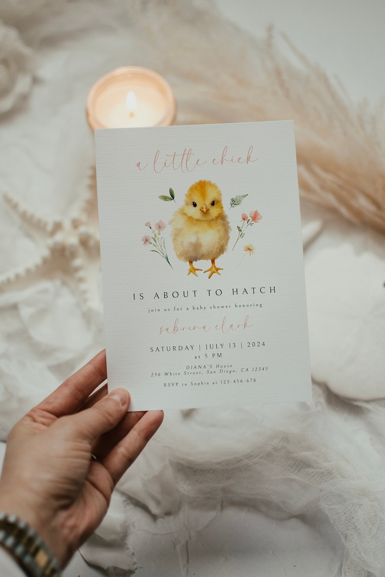 May include: A baby shower invitation with a watercolor illustration of a yellow chick with pink flowers. The text reads "a little chick is about to hatch" and includes the name "Sabrina Clark", the date "Saturday, July 13, 2024", the time "at 5 PM", the location "Diana's House, 256 White Street, San Diego, CA 12345", and the RSVP information "RSVP to Sophie at 123-456-678".
