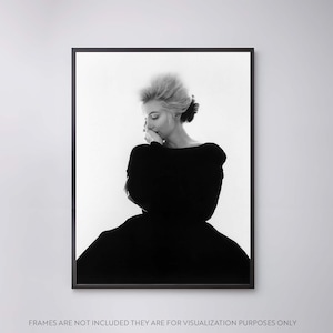 May include: Black and white photograph of a woman in a black dress, looking down with her hand on her chin.