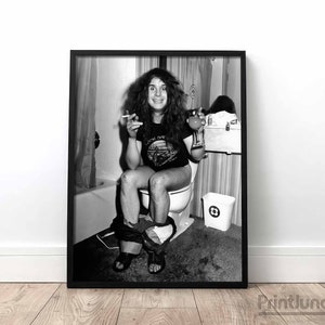 May include: Black and white photo of a man sitting on a toilet in a bathroom. He is wearing a t-shirt with the words "Don't Fear The Reaper" on it. He is holding a cigarette in one hand and a glass in the other.