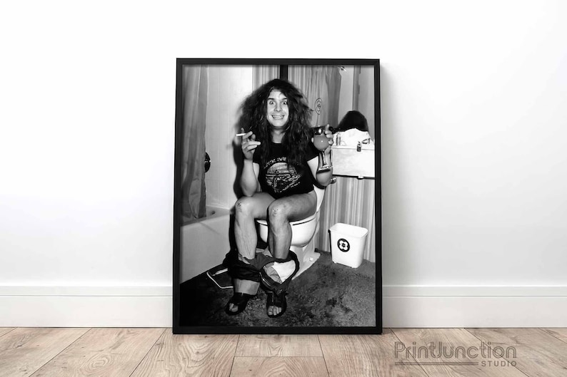 May include: Black and white photo of a man sitting on a toilet in a bathroom. He is wearing a t-shirt with the words "Don't Fear The Reaper" on it. He is holding a cigarette in one hand and a glass in the other.