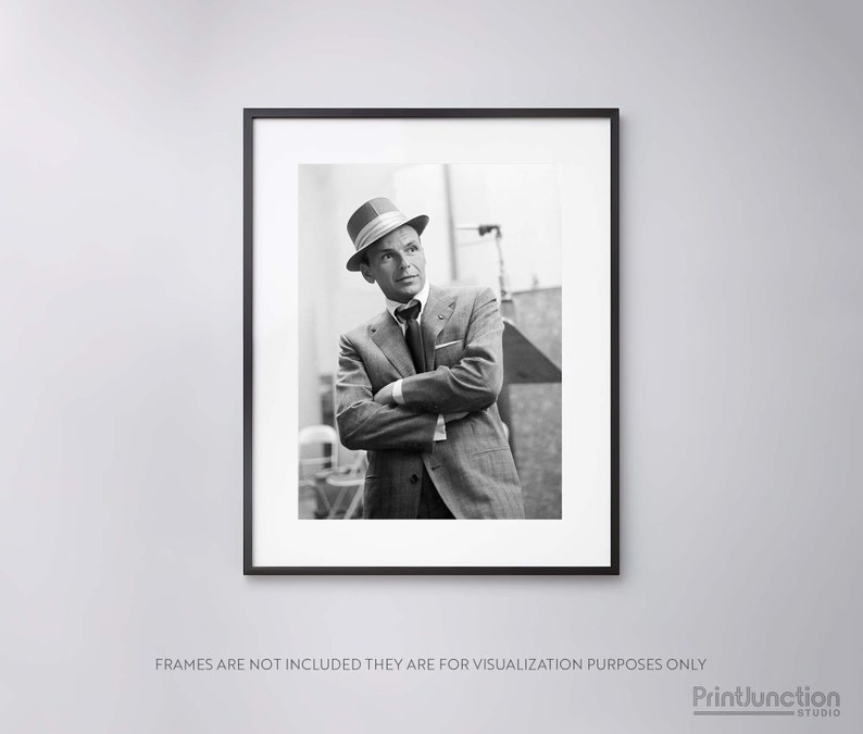 Pu&ograve; includere: Fotografia in bianco e nero di un uomo in abito e cappello. &Egrave; in piedi con le braccia incrociate e guarda di lato.