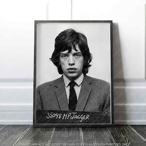 May include: A black and white framed portrait of a man in a suit and tie. The image includes a sign with the text "35098 MP JAGGER". The portrait is displayed on a wooden surface.