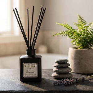 May include: A black square essential oil diffuser with black reeds, a small potted fern, and a stack of smooth stones. The diffuser has a label that reads "Made Pure Co. Taiga". A sprig of lavender rests nearby.