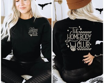 May include: Black sweatshirt with a gold graphic that says "The Homebody Club" with a skeleton hand making a rock and roll sign. The graphic is on a black and white checkered background.