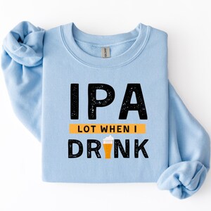 May include: A light blue sweatshirt with the text "IPA LOT WHEN I DRINK" in black block letters. The design includes an orange rectangle and a graphic of a beer glass with foam.
