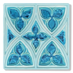May include: A square ceramic tile with a blue and white geometric design. The tile features a repeating pattern of four-leaf clover shapes.