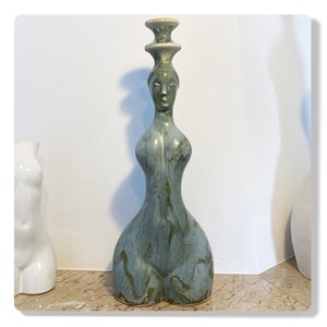 Könnte beinhalten: Eine Keramikskulptur einer Frau mit grüner und blauer Glasur. Die Skulptur hat ein schlichtes, stilisiertes Design und ist ein einzigartiges Kunstwerk.