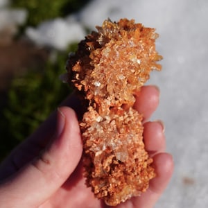 May include: A cluster of orange and white crystals, resembling a small, rough, rock formation.